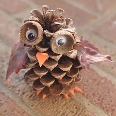 an owl made out of pine cones sitting on top of a brick floor with eyes