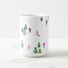 a white coffee mug with skiers and trees on it