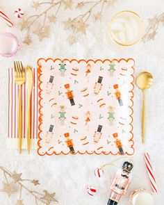 a place setting with candy canes, goldware and other holiday decorations on the table