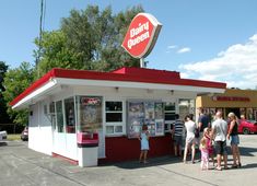 people are standing in front of a donut shop with a sign above the store