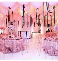 a room filled with balloons and tables covered in pink tablecloths for a party