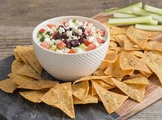 a white bowl filled with salad next to tortilla chips on a cutting board