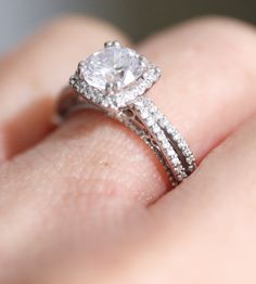 a close up of a person's hand with a diamond ring on their finger