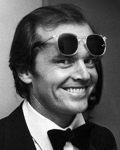 a man in a tuxedo and bow tie with sunglasses on his face smiling