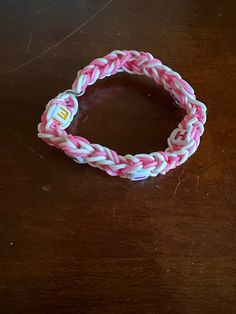 a pink and white bracelet sitting on top of a wooden table