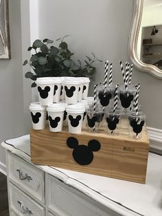 mickey mouse cups with black and white striped straws on a wooden box in front of a mirror