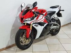 a red and white motorcycle parked next to a wall