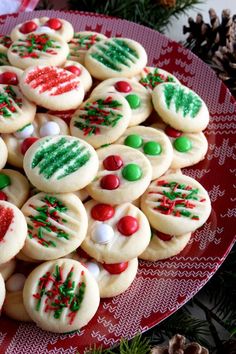 decorated cookies on a red plate with pine cones