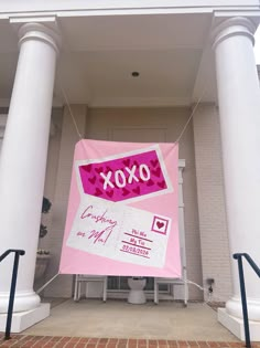 a pink and white banner hanging from the side of a building next to some stairs