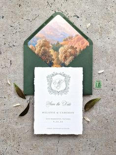 the wedding stationery is set on top of an envelope with leaves and foliage around it