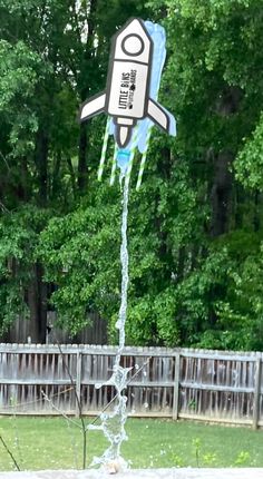 a kite shaped like a rocket flying through the air with water coming out of it