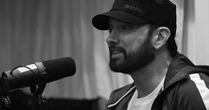 a man with a beard and baseball cap in front of a microphone