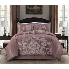 a bed in a bedroom with pink comforter and pillows