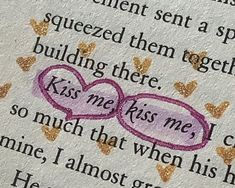 an open book with two hearts and words written in pink on the page, which reads kiss me