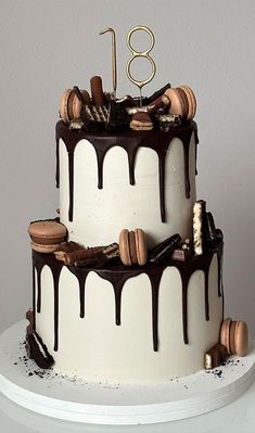 a three tiered cake with chocolate icing and cookies on top