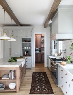 a kitchen with an area rug in the middle and wooden cabinets on both sides, along with stainless steel appliances