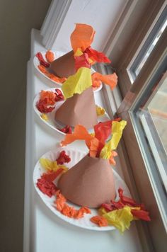 two paper plates with hats on them are sitting next to a window sill, decorated with orange and yellow flowers