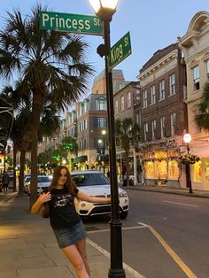 a woman standing under a street sign next to a lamp post on a city street