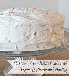 a cake with white frosting and sprinkles on top sitting on a glass plate