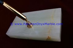 a pen sitting on top of a white marble block with a gold colored metal tip