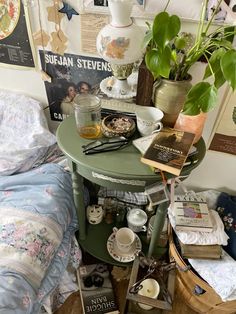 a small table with books and magazines on it next to a bed covered in blankets