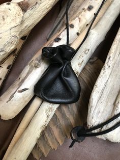 a small black bag sitting on top of a wooden table next to driftwood sticks