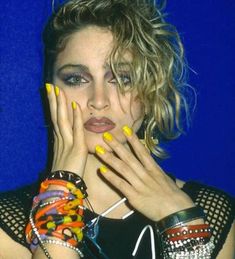 a woman with her hands on her face and colorful jewelry around her neck, posing for the camera