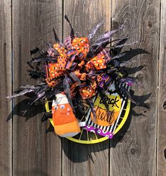 a trick or treat wreath on top of a wooden fence with halloween decorations around it