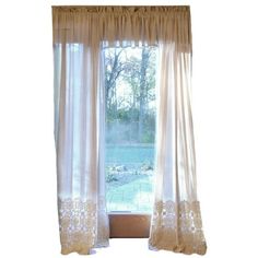 an open window with white curtains and lace trims on the curtain rod, in front of a pool