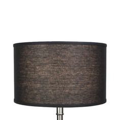 a lamp with a black shade on top of it and a white base behind it