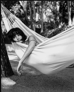 a woman laying in a hammock between two trees