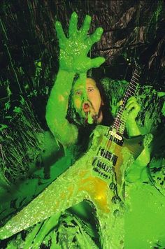 a man covered in green paint holding a guitar