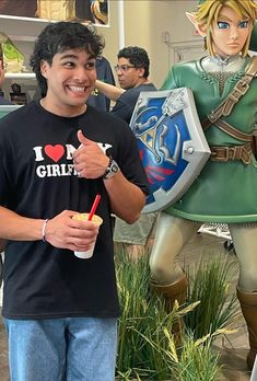 a man standing in front of a statue holding a drink and pointing to the side