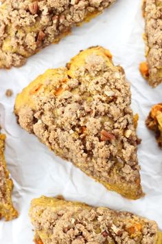 several pieces of food sitting on top of white paper with crumbled toppings