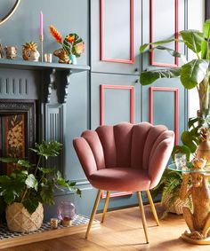 a living room with blue walls and pink chairs in front of a fireplace, potted plants