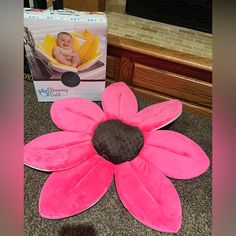 a large pink flower sitting on top of a floor next to a box of baby products