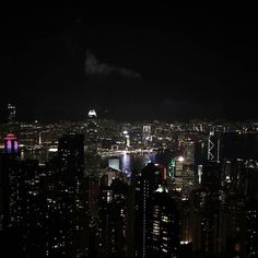 the city skyline is lit up at night with bright lights and skyscrapers in the background