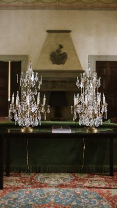 the table is covered with crystal candlesticks on top of a green cloth in front of a fireplace