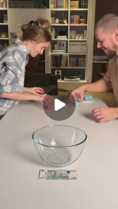 a man and woman sitting at a table with an egg in a bowl on it