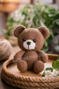 a brown teddy bear sitting on top of a wooden tray next to flowers and yarn