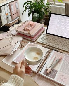 a person sitting at a desk in front of a laptop computer with papers and notebooks on it