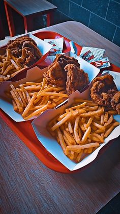 three trays filled with fried chicken and french fries