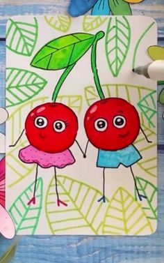 two cherries on a white paper with green leaves and blue flowers in the background