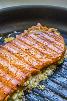 a piece of meat is being cooked on a grill with some sauce and seasoning