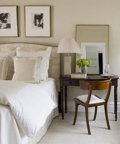 a bedroom with two pictures on the wall and a desk in front of the bed