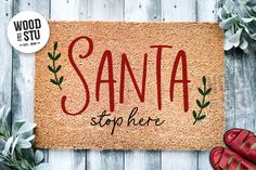 a door mat with the words santa on it next to red shoes and succulents