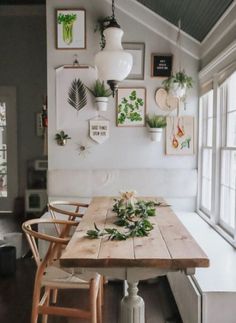 a dining room table and chairs in front of a window with potted plants on it