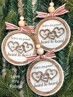 three ornaments hanging from a christmas tree with hearts and words on the front, one is made out of wood