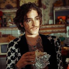 a young man with curly hair is holding food