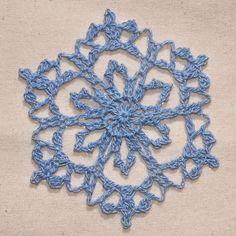 a blue crochet doily on a beige background with white stitching in the center